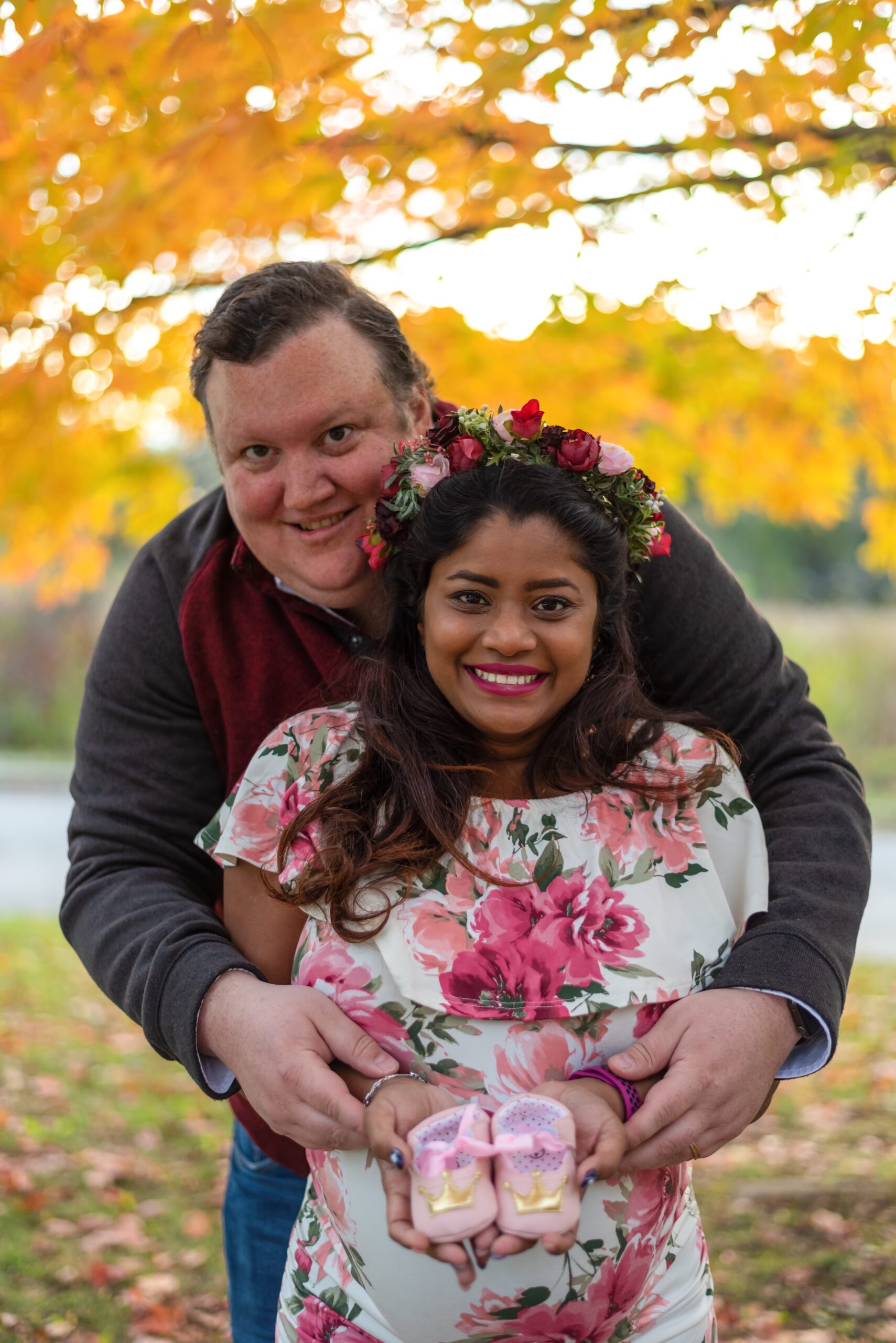Fall maternity portrait of young couple with pink baby girl shoes